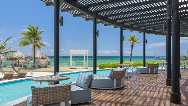 A poolside area with lounge chairs, a small pool, and a view of the ocean.