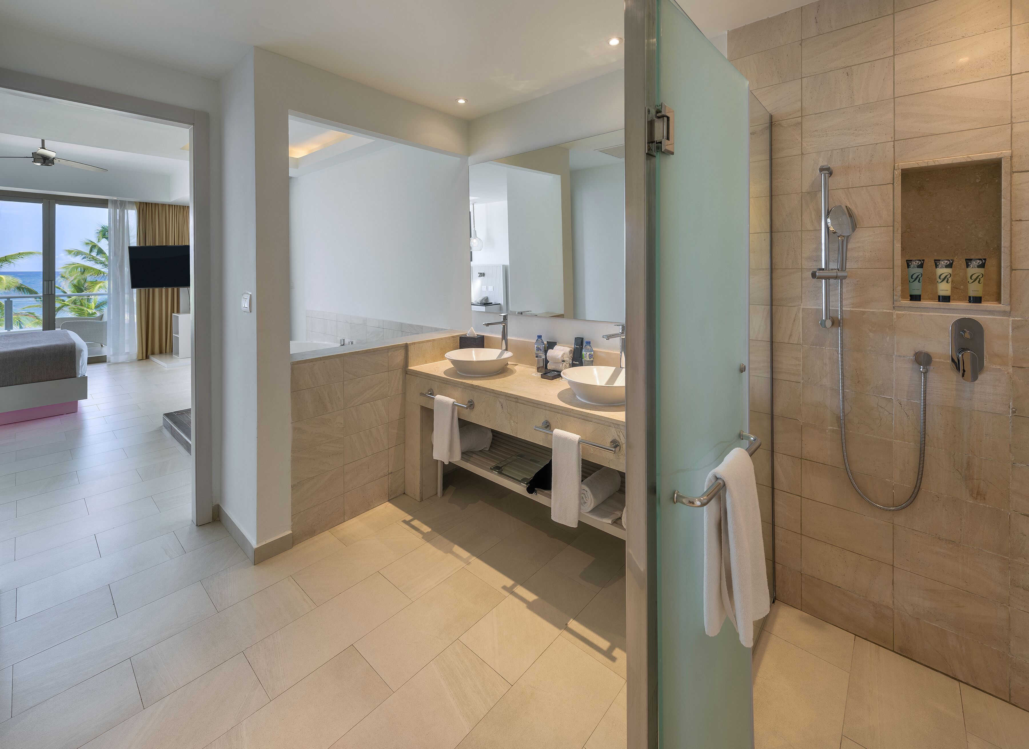 A modern bathroom with a glass-enclosed shower, two sinks, and a large mirror.