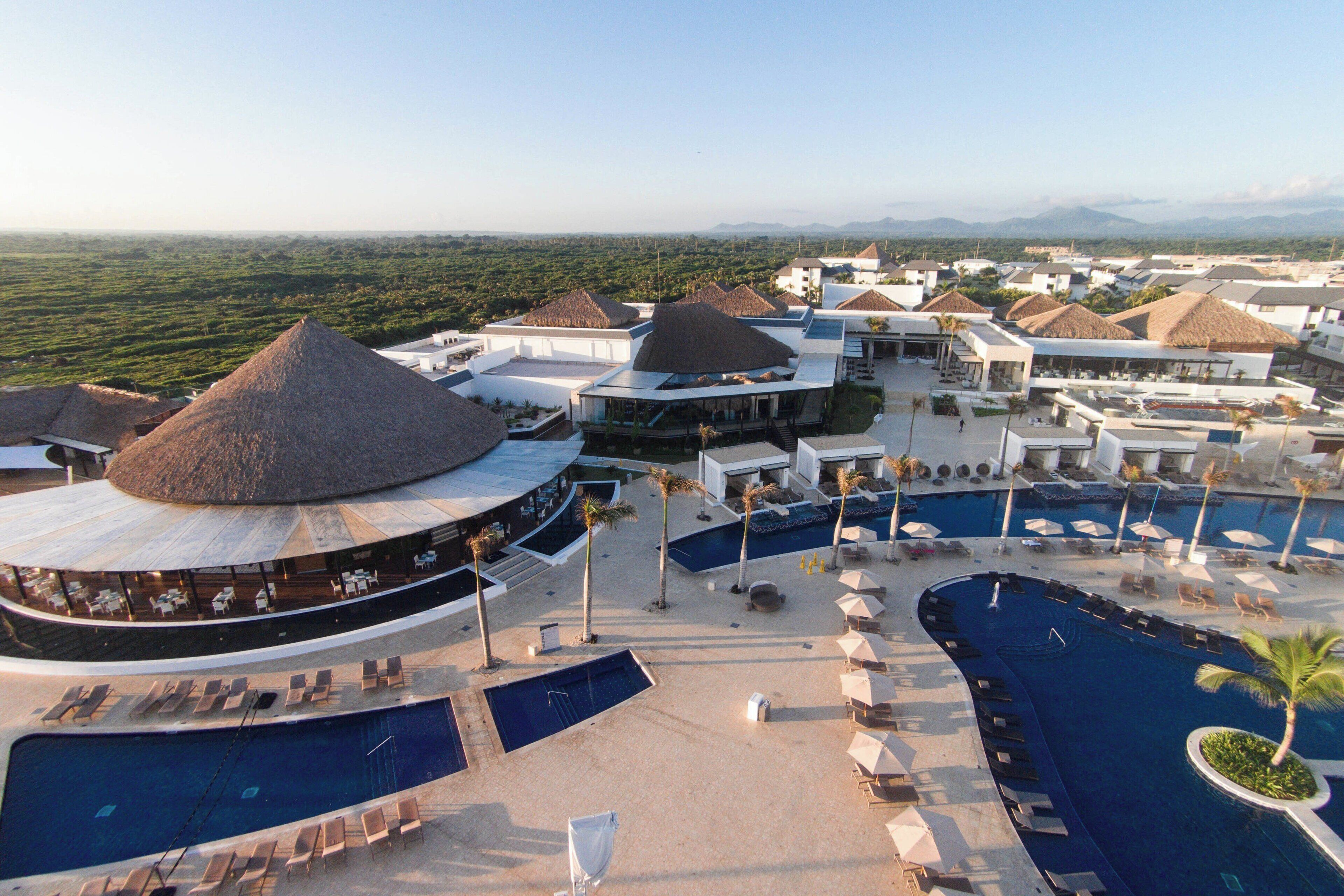A resort with multiple swimming pools, sun loungers, and thatched-roof structures.