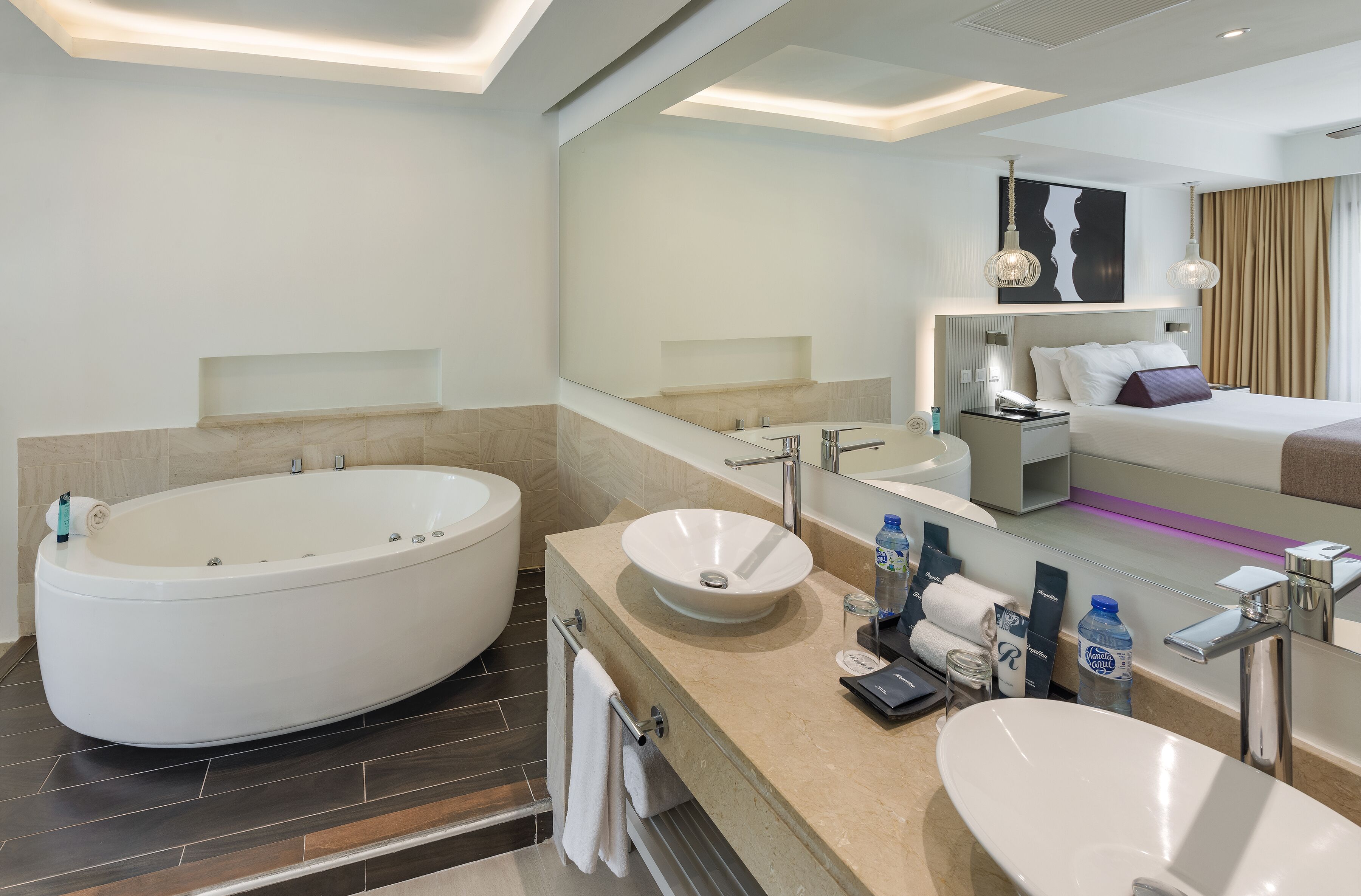 A modern bathroom with a large bathtub, a sink, and a mirror.