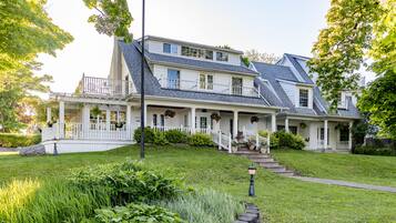 A two-story house with a covered porch, a front yard with a stone border, and a street lamp.