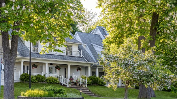 A two-story house with a front porch, a staircase, and a well-maintained lawn. - Chestnut Inn Bed and Breakfast (Niagara Falls)