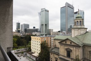 Kaupunkikuva, jossa on moderneja pilvenpiirtäjiä, historiallinen rakennus kupolilla sekä asuin- ja liikerakennusten yhdistelmä.