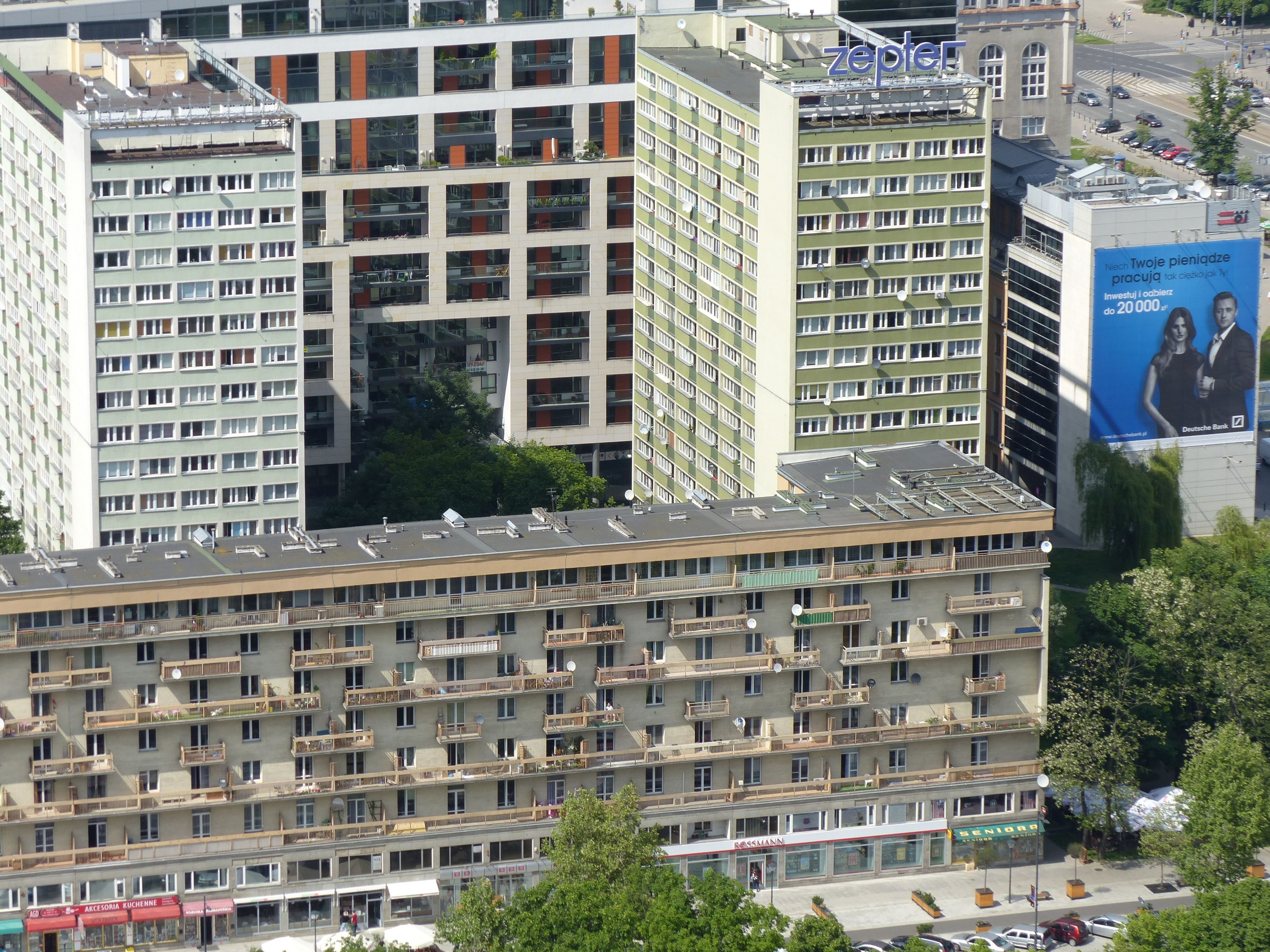 A multi-story building with numerous balconies and a large billboard on the side.