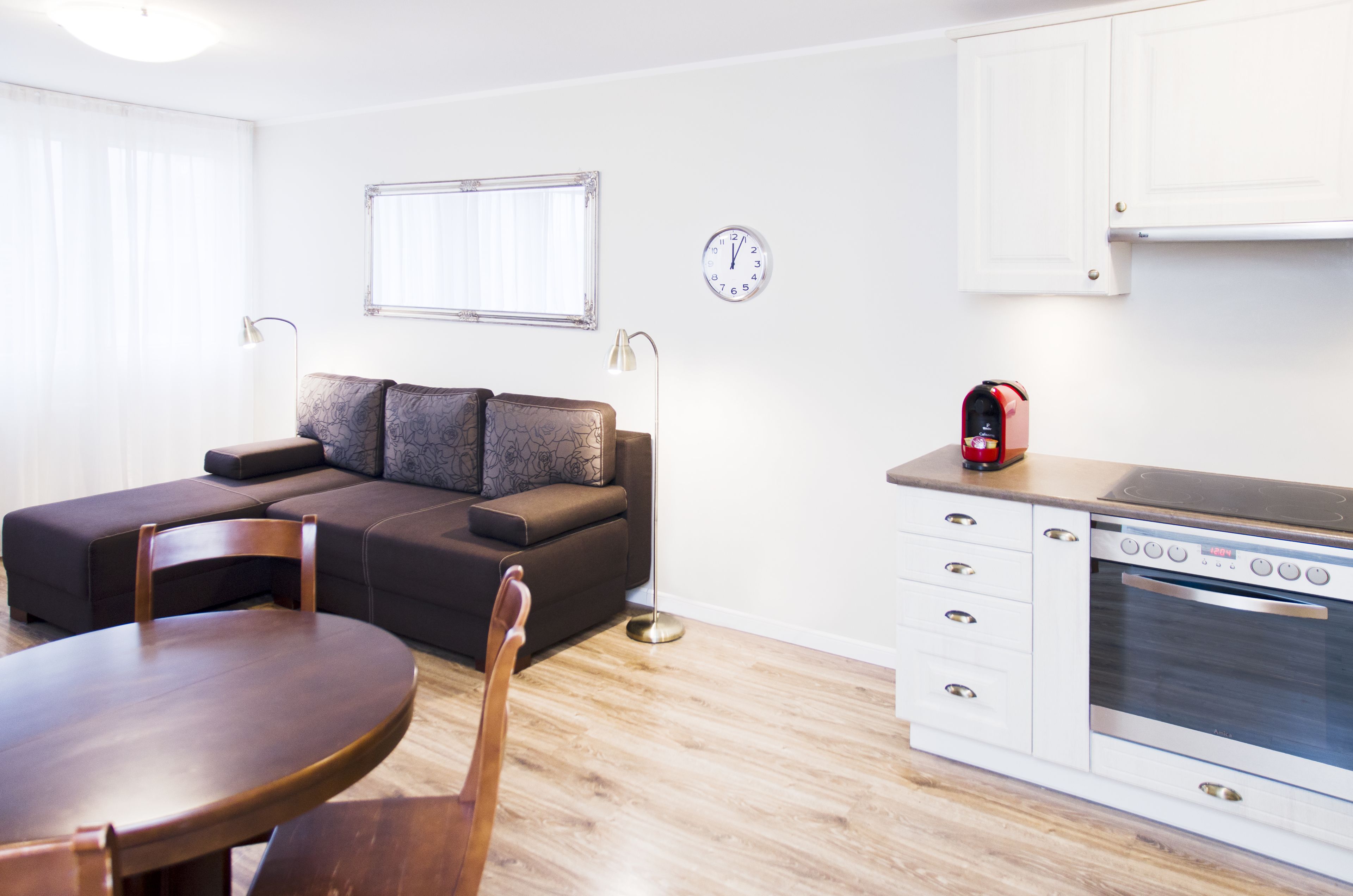 Un salon moderne comprenant un canapé, une table à manger et un coin cuisine avec une cuisinière et des placards.