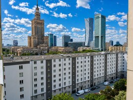 A high-rise building with a modern design, surrounded by other tall buildings and a clear blue sky.