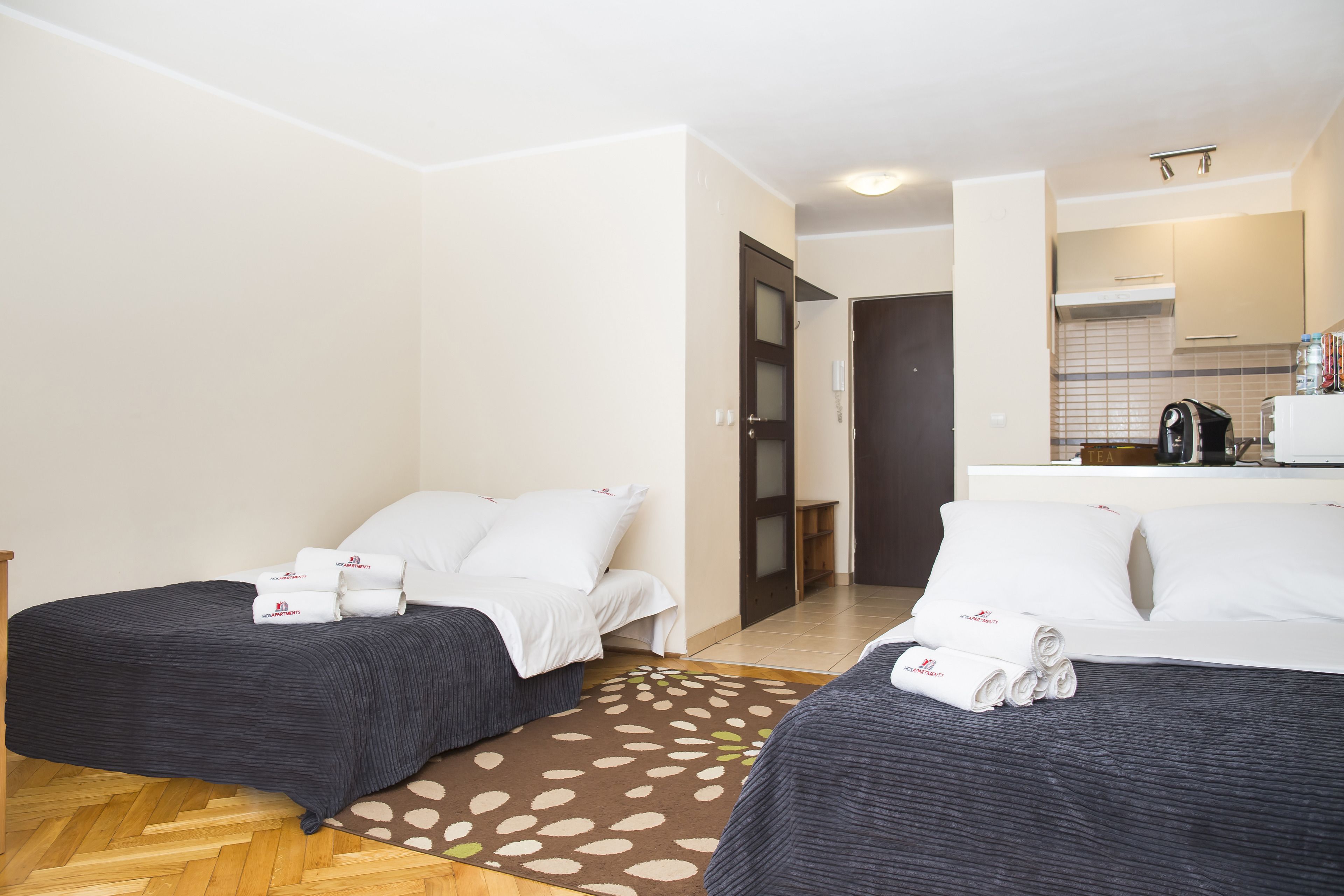 Een hotelkamer met twee bedden, een kleine kitchenette en een badkamer die door een open deur zichtbaar is.