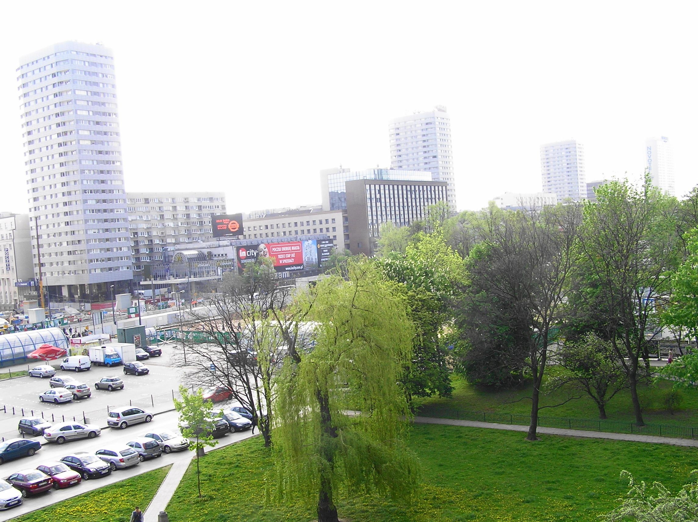 A parking lot with several cars and a few trees in the foreground.
