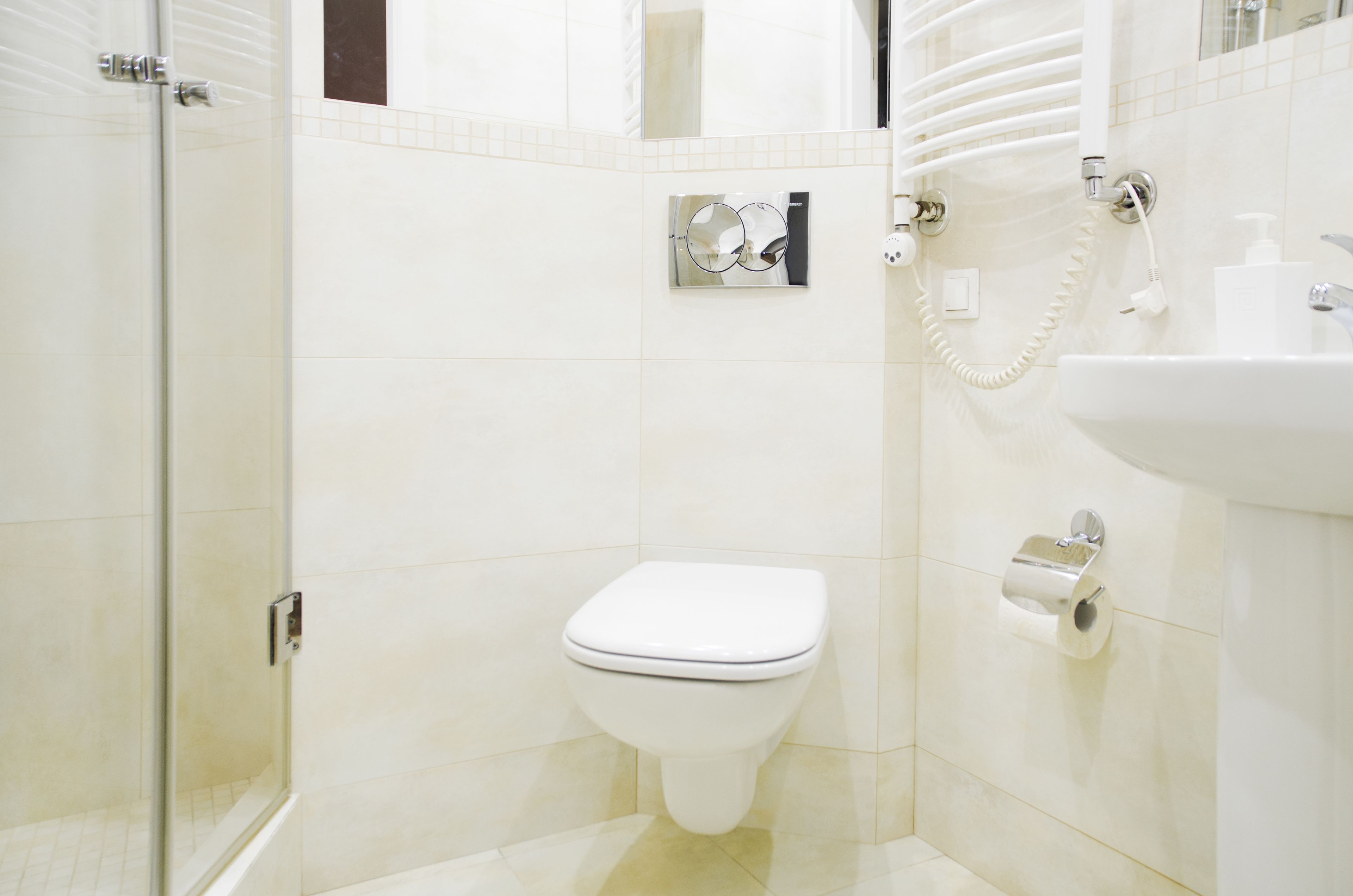 A modern bathroom with a glass shower enclosure, a white toilet, and a sink with a soap dispenser.