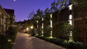 A nighttime pathway flanked by illuminated vertical light fixtures and trees, leading to a building with a brick facade. - Relais & Chateaux Yihe Mansions (Nanjing)