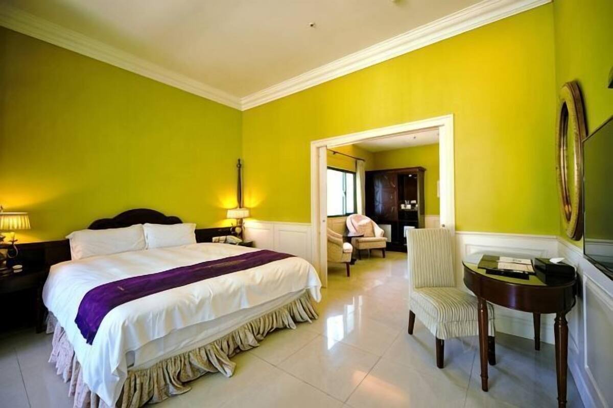 Una habitación de hotel con cama, mesitas de noche, una silla y una pequeña mesa.