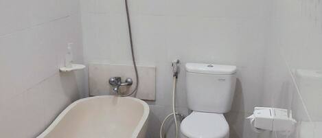 Une salle de bain avec une baignoire sur pieds, des toilettes et une douche. Le sol est recouvert d’un motif de mosaïque.