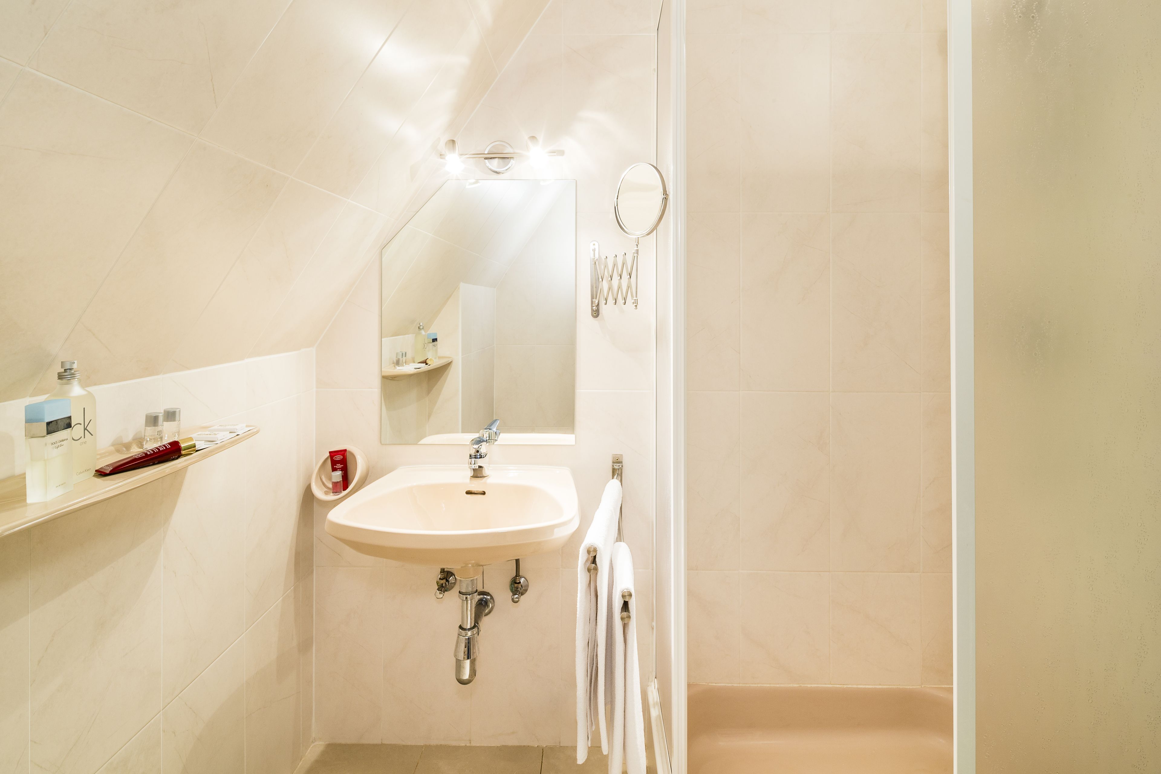 Un baño con lavamanos, espejo y toallero.