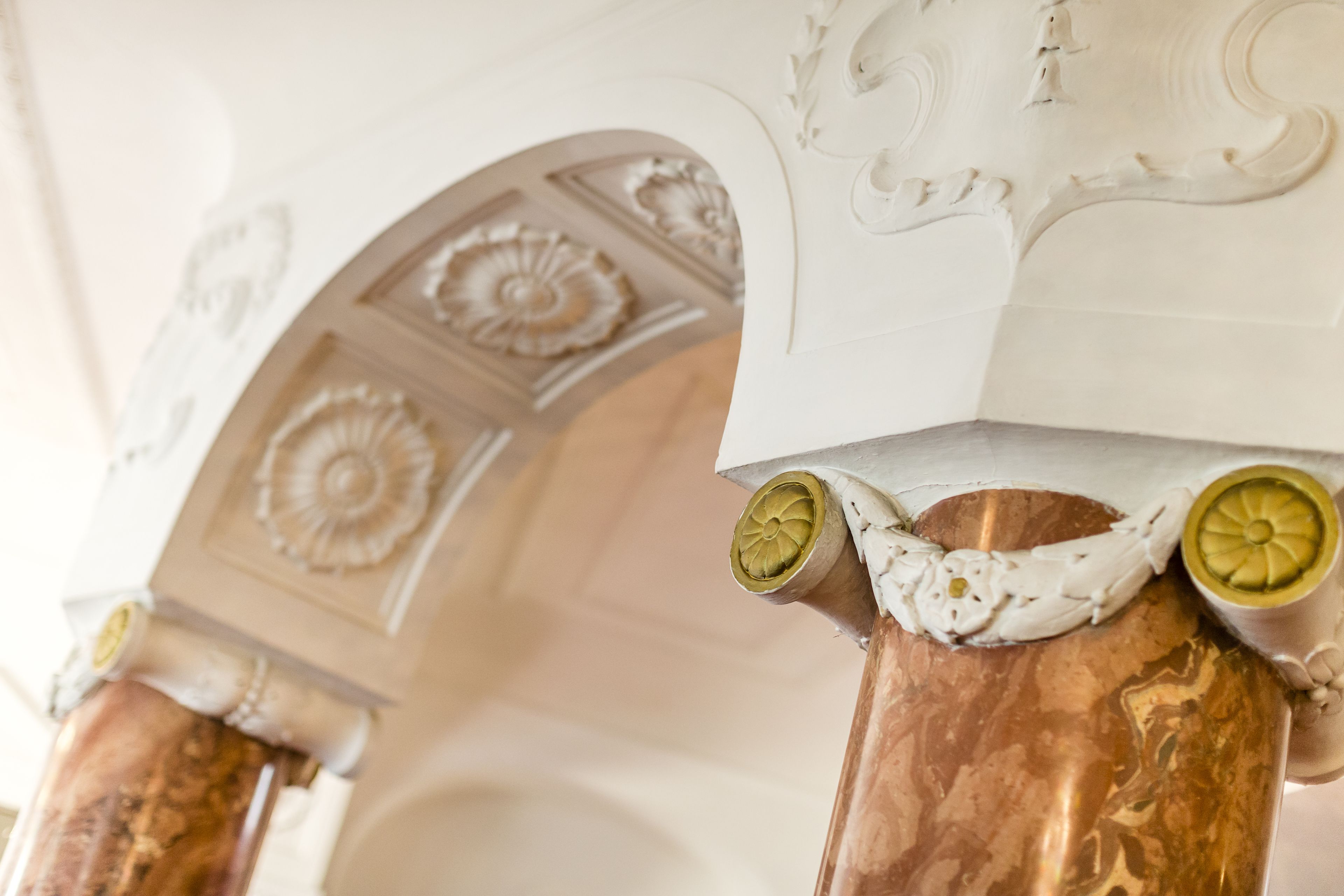 Ein Detailaufnahme einer Marmorsäule mit aufwendigen Schnitzereien und einem dekorativen Bogen.