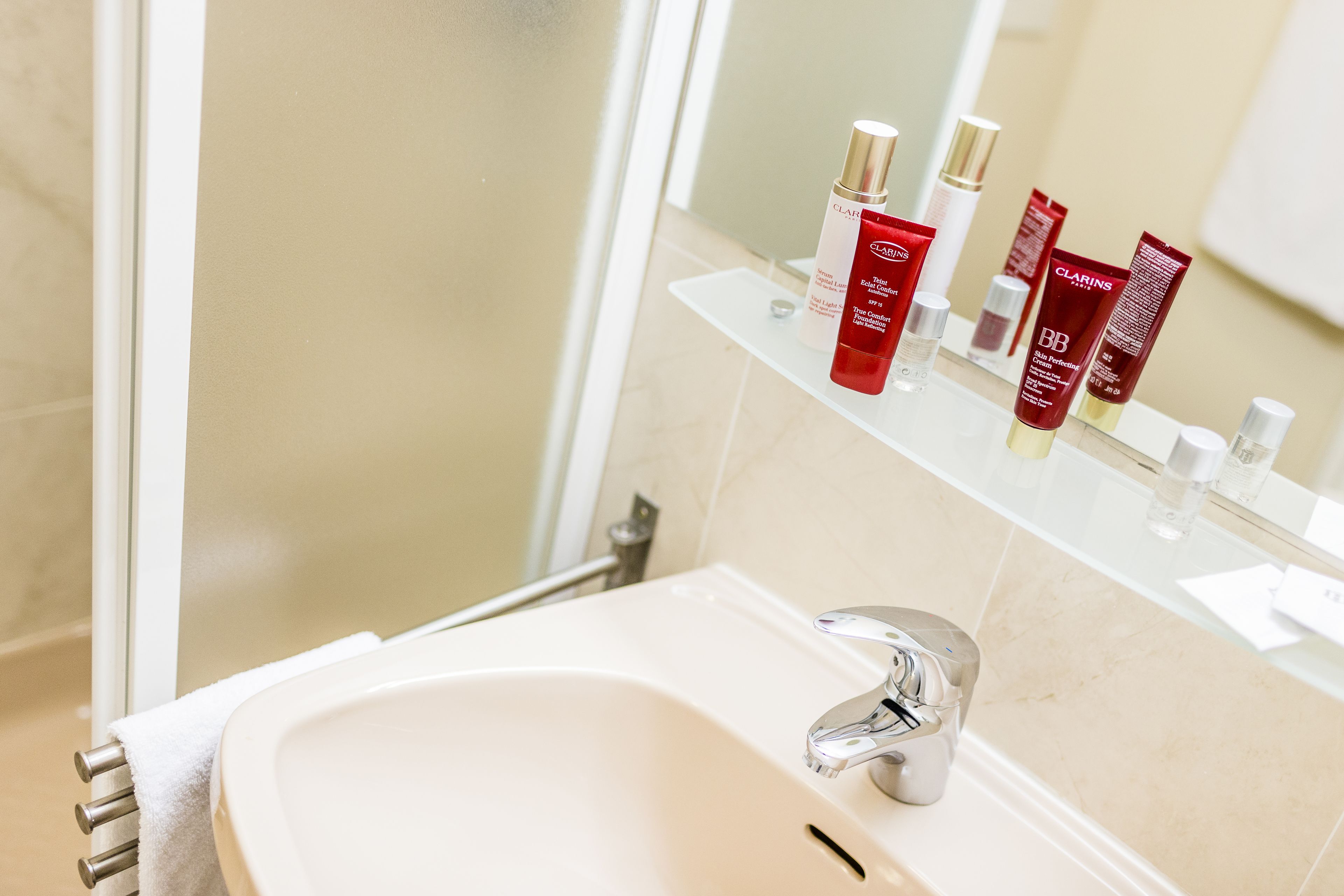 Un bagno con lavandino, specchio e articoli da toilette su uno scaffale.