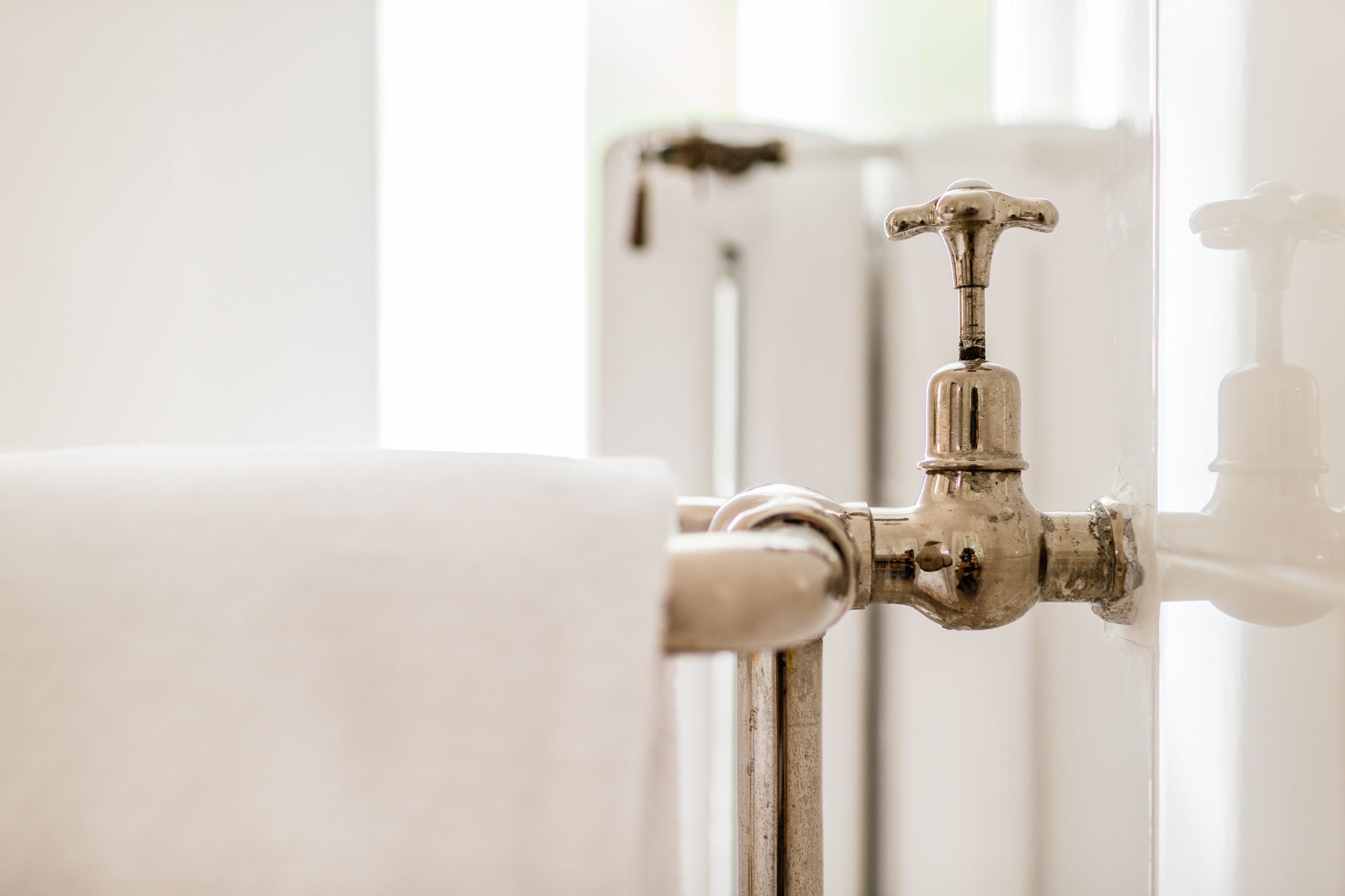 A bathroom with a white radiator, a visible water tap, and a toilet paper holder.