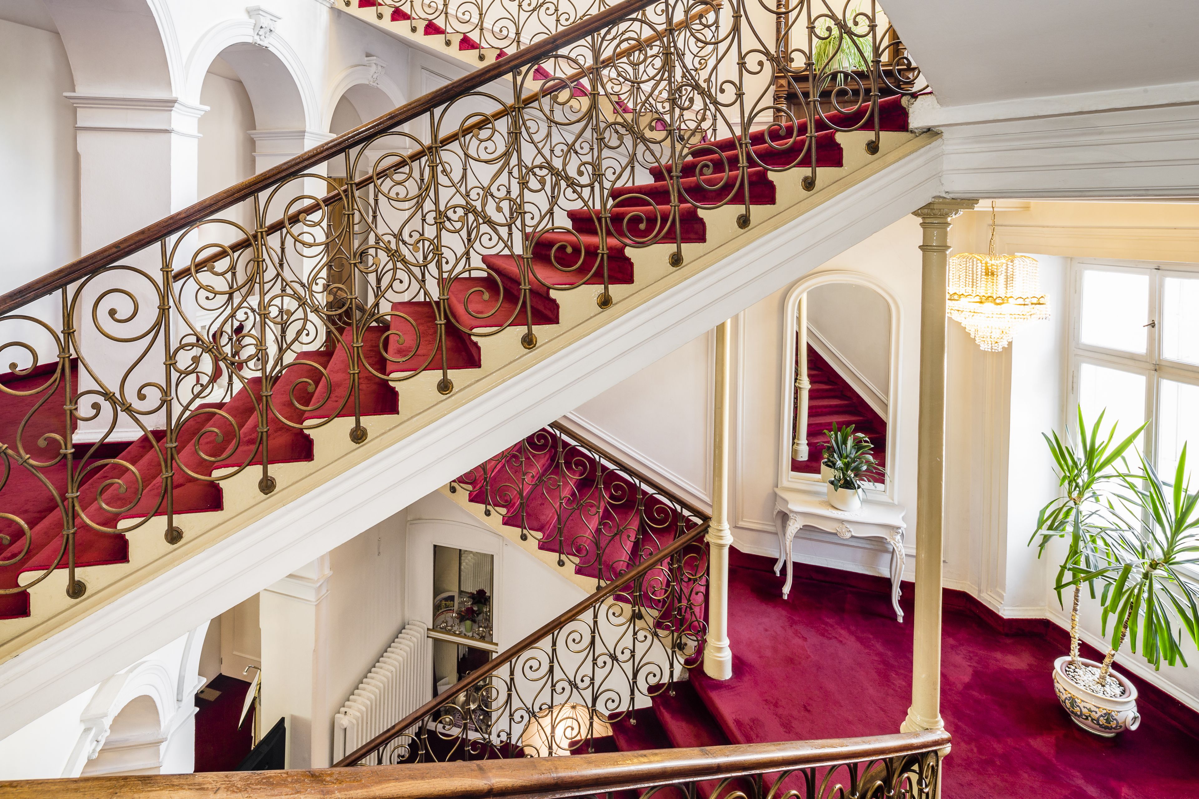 A grand staircase with ornate metal railings and red carpeted steps.