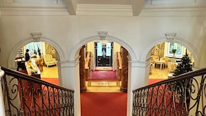 A grand staircase with ornate railings, leading to a well-lit lobby area with seating and a Christmas tree. - Grand Hotel Bellevue - adults only (Merano)