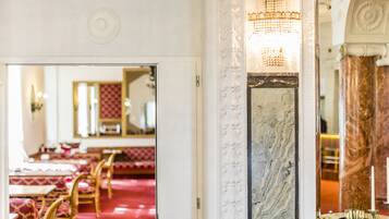 Un'elegante hall d'albergo con tappeto rosso, colonne di marmo e un lampadario.