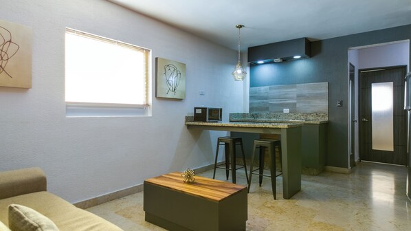 Una cocina moderna con una isla integrada, taburetes de bar y una lámpara colgante.