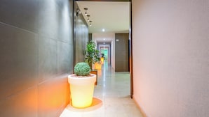 Un couloir au design moderne, agrémenté d’une plante en pot et d’un lampadaire.
