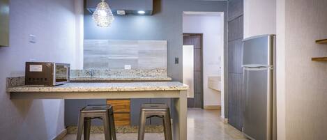 Una cocina moderna con encimeras de granito, electrodomésticos de acero inoxidable y una lámpara colgante.