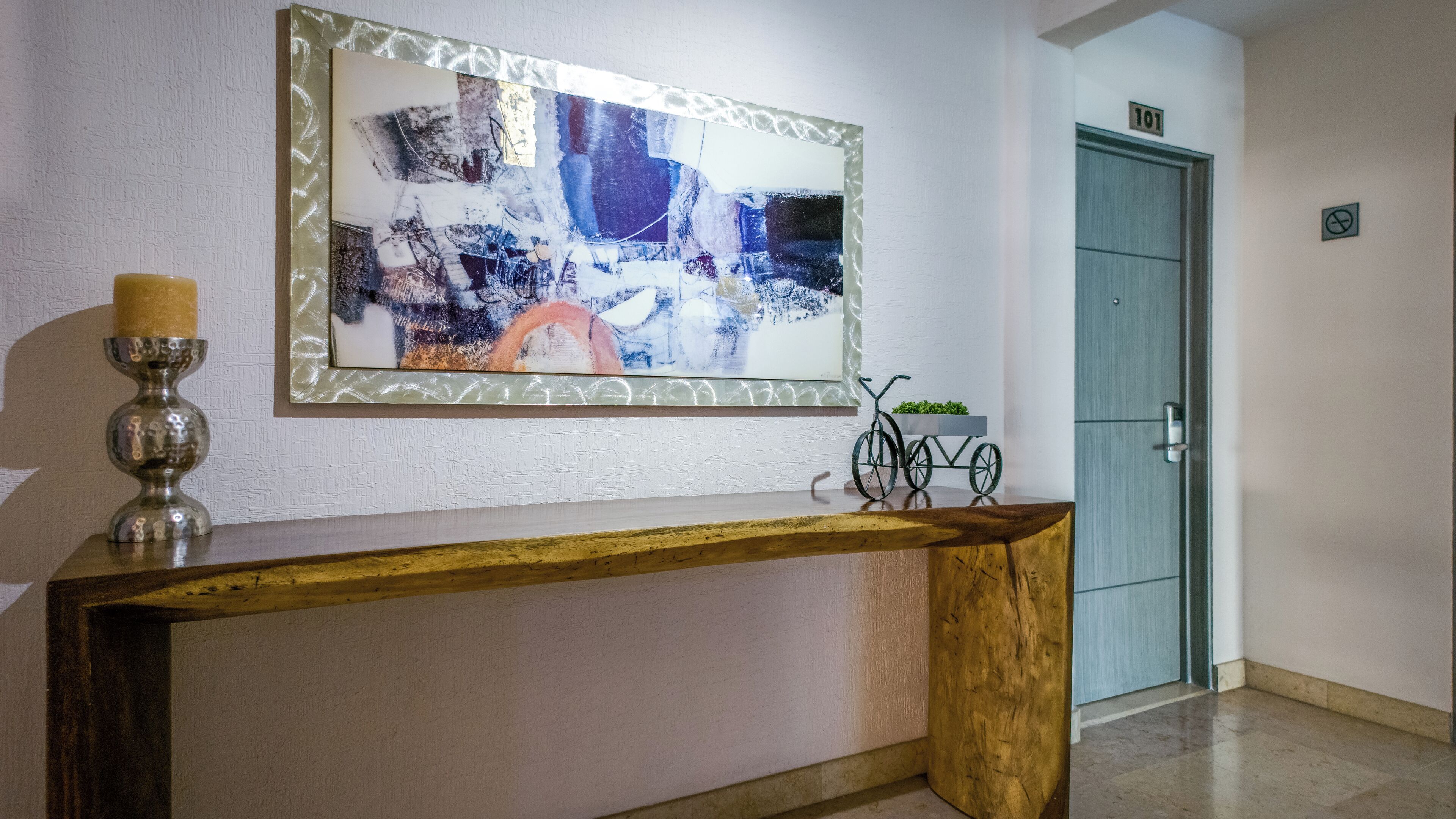A reception desk with a modern abstract painting, a metal candelabra, and a small bicycle decoration.