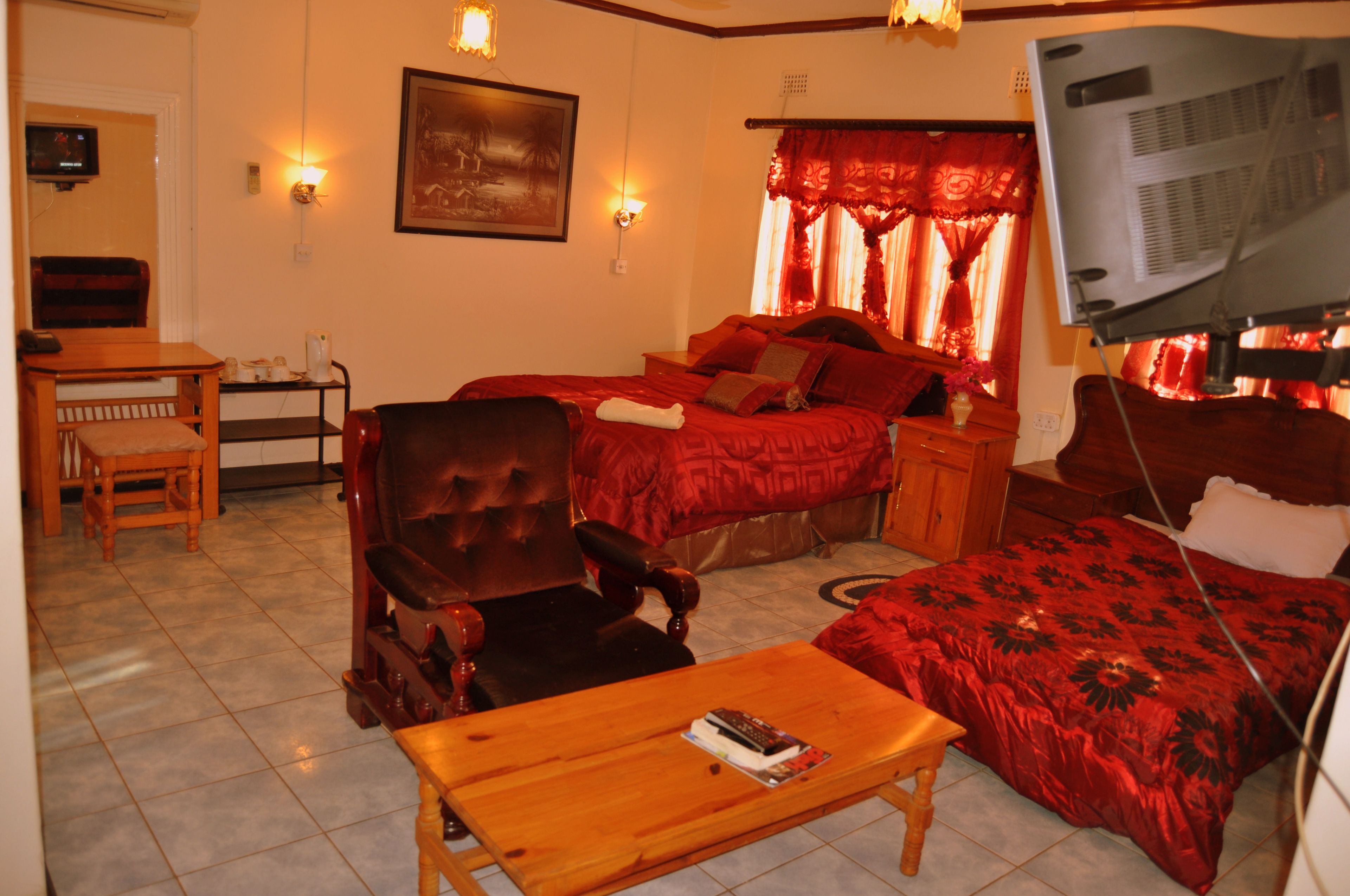 A room with two beds, a wooden chair, a small table, and a TV mounted on the wall.