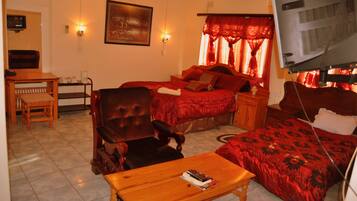 A room with two beds, a wooden chair, a small table, and a TV mounted on the wall.