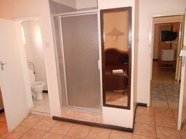 A bathroom with a toilet, a shower, and a bed with a towel.