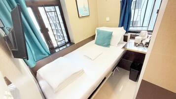 Une petite chambre avec un lit simple, une fenêtre, un bureau et une chaise.