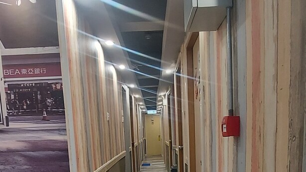 A corridor with tiled flooring and walls painted in a striped pattern. - Apple Hostel (Kowloon)