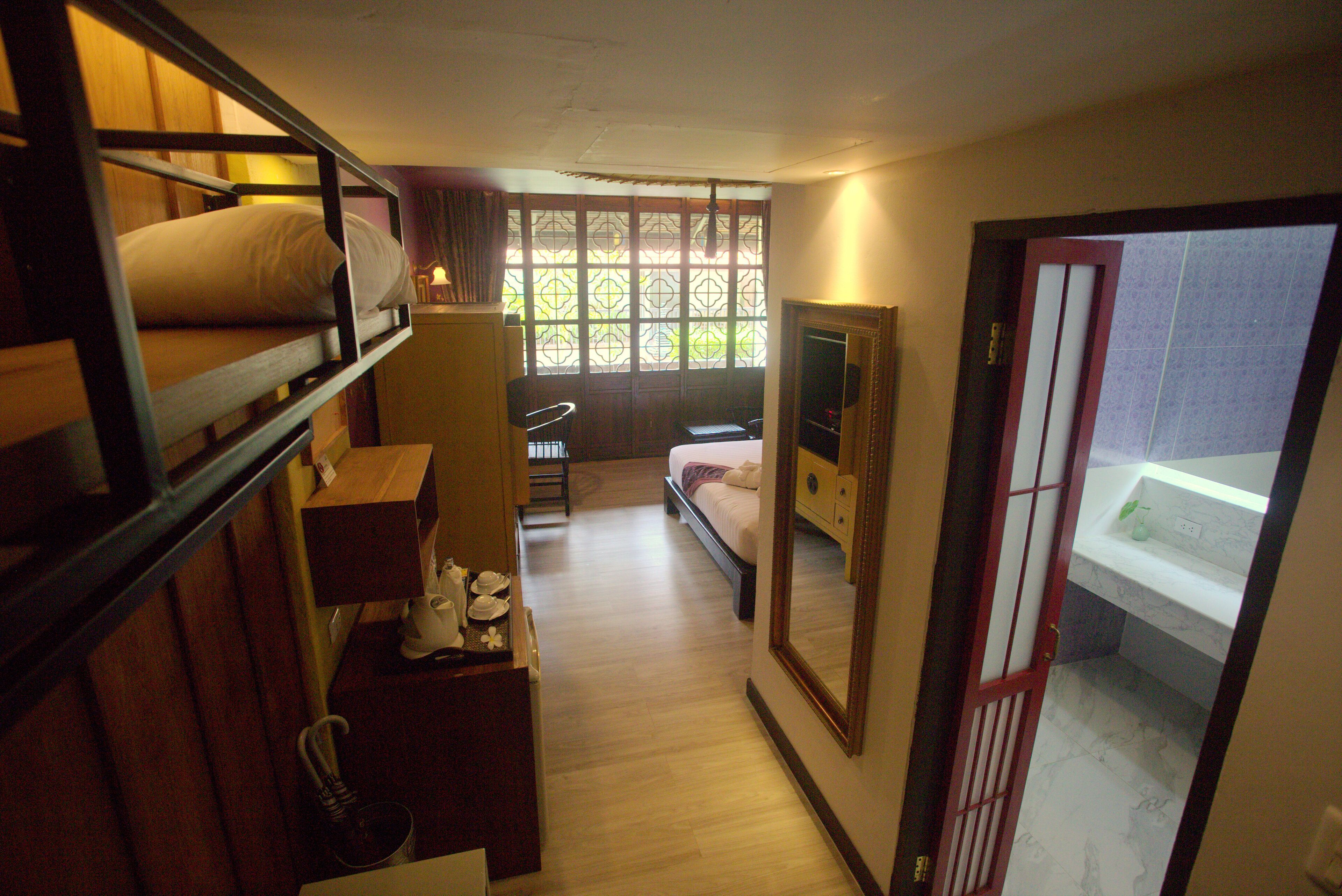 Camera d'albergo compatta con un letto a castello, una scrivania piccola con una sedia, una finestra con vista e un bagno con specchio e lavandino.
