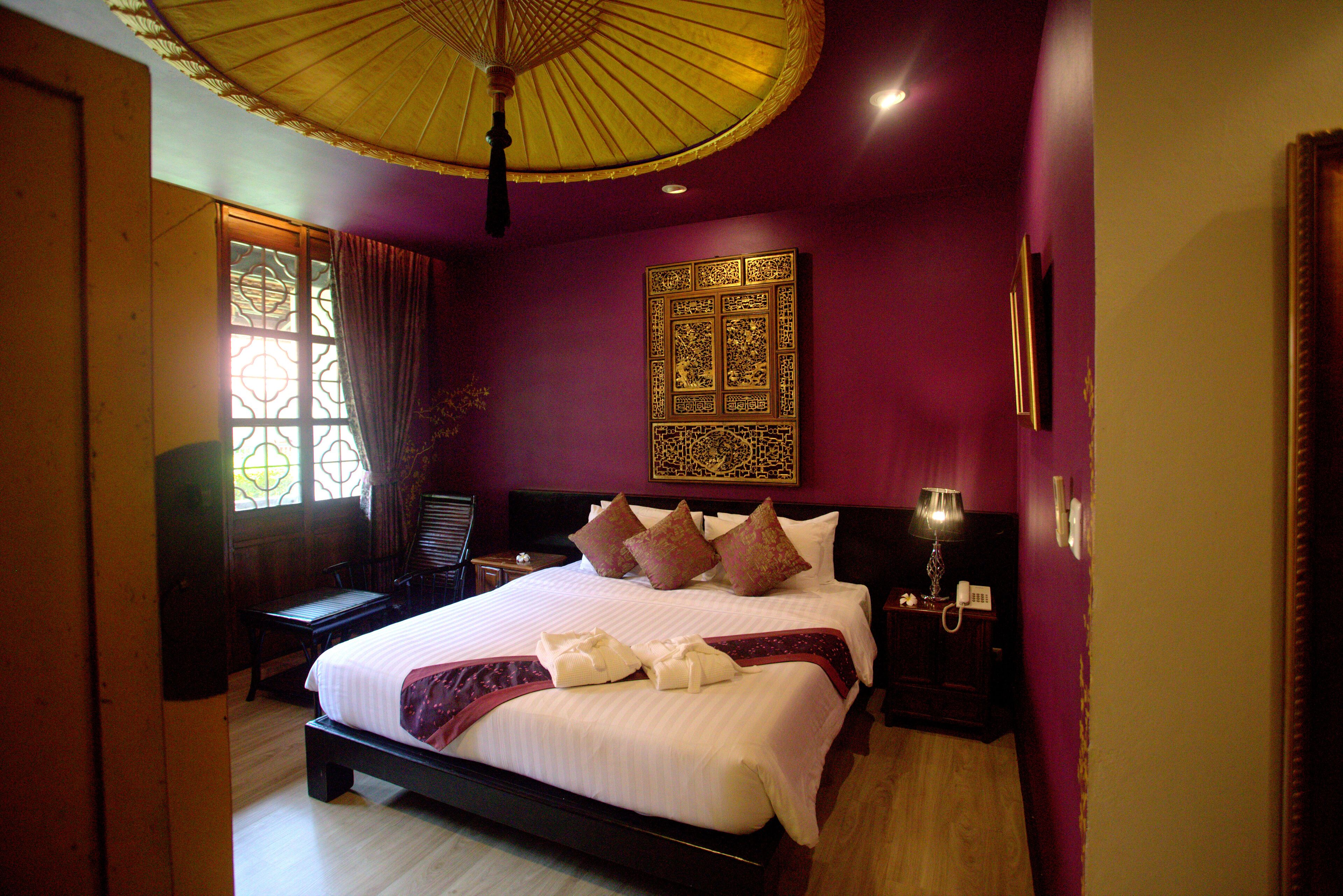 Una habitación de hotel con una cama grande, una mesita de noche, una lámpara y un adorno en la pared.