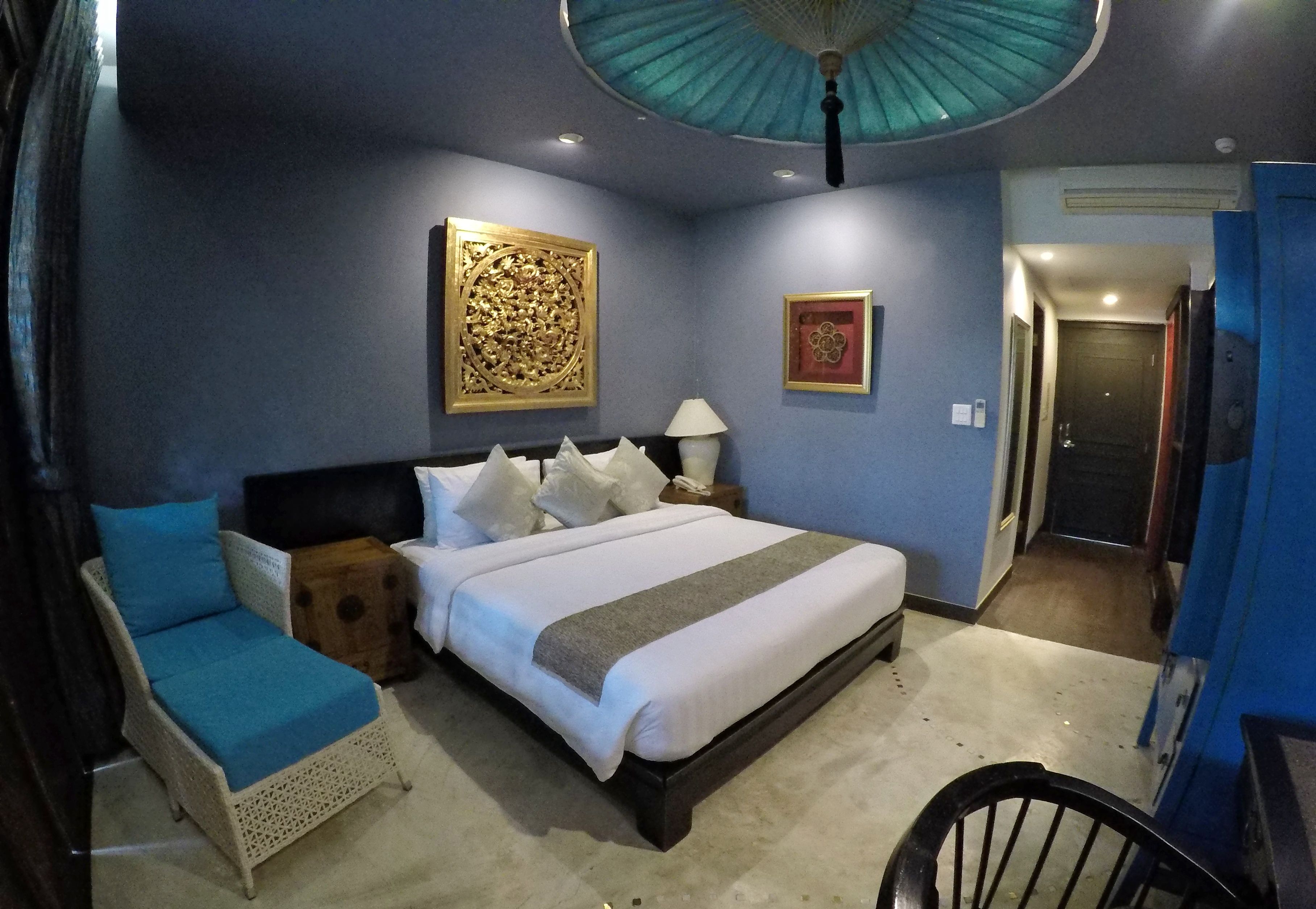 A bedroom with a bed, a nightstand, a chair, and a wall art piece.
