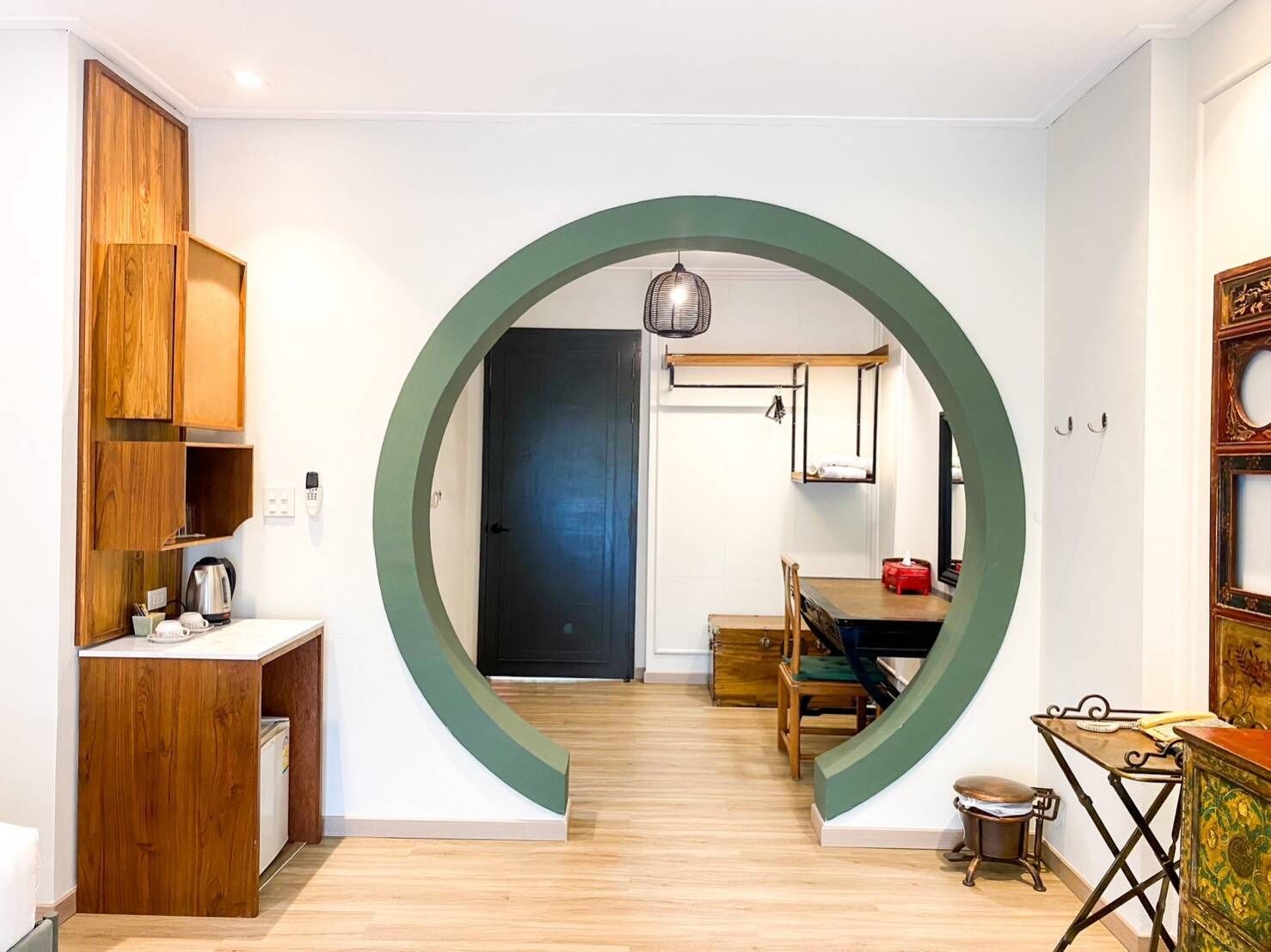 A modern kitchen with wooden cabinets, a dining area with a table and chairs, and a circular archway leading to a living space.