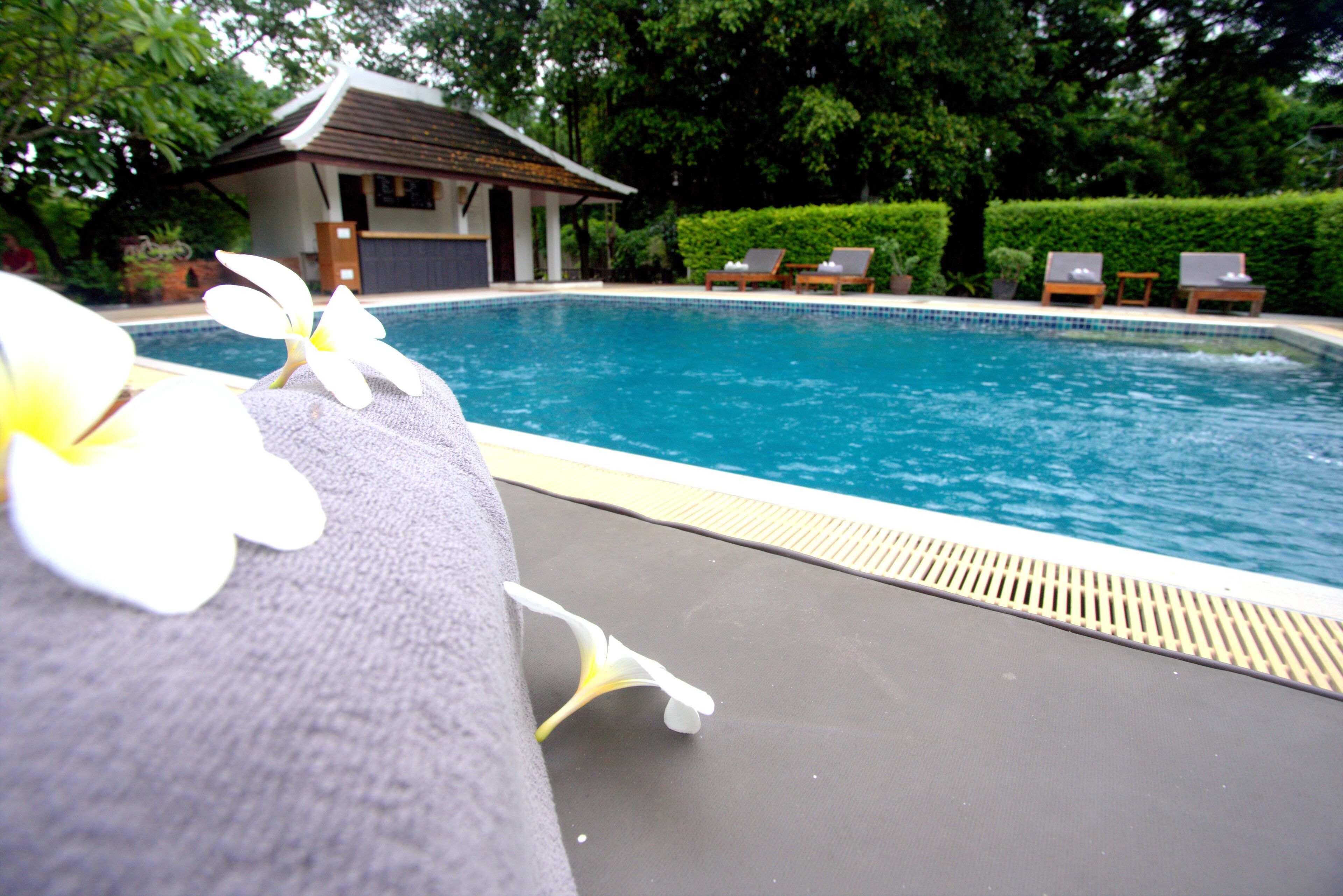 Un espace aménagé au bord de la piscine, avec des chaises longues et un petit bâtiment en arrière-plan.