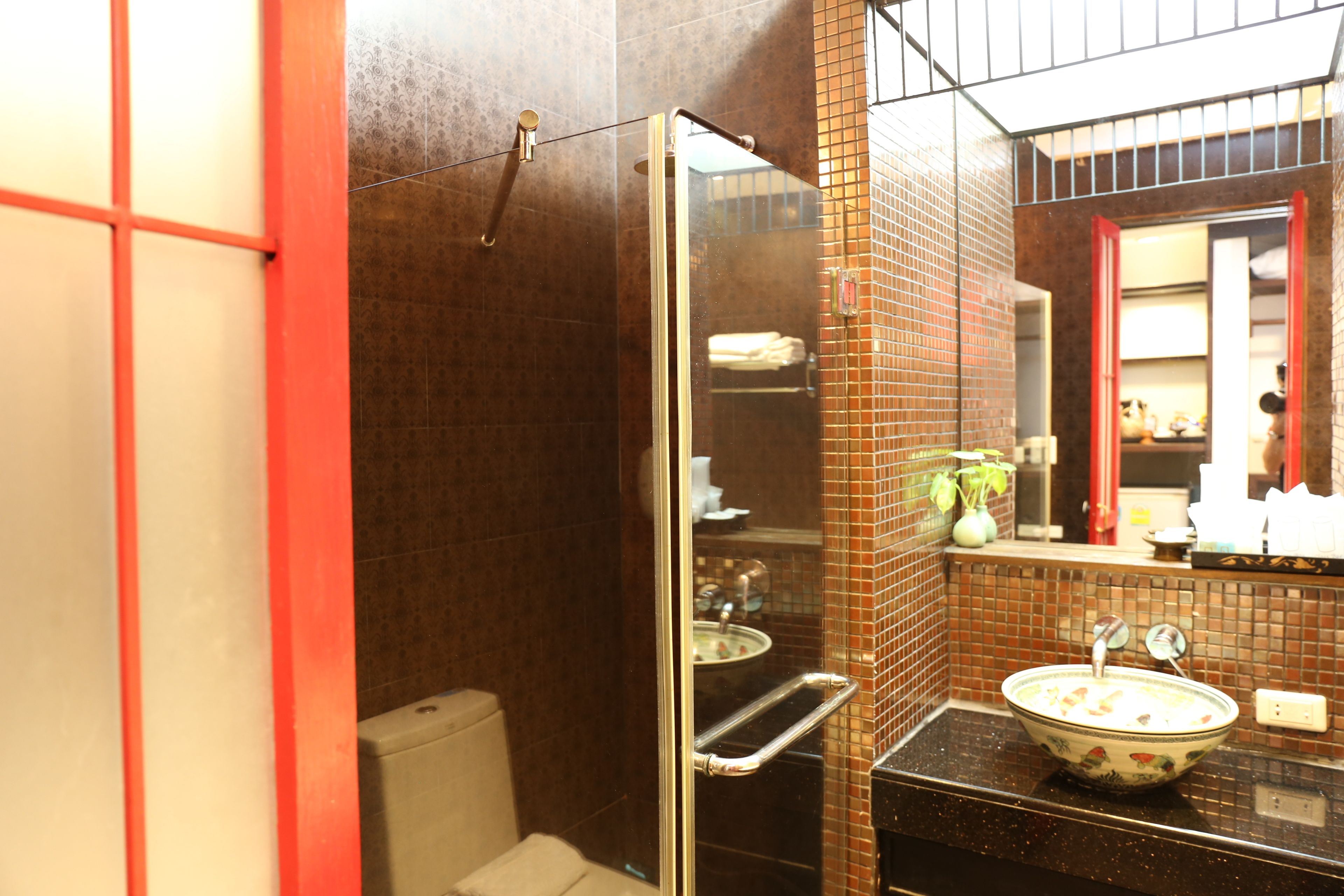 A bathroom with a glass shower enclosure, a sink with a decorative bowl, and a mirror above the sink.