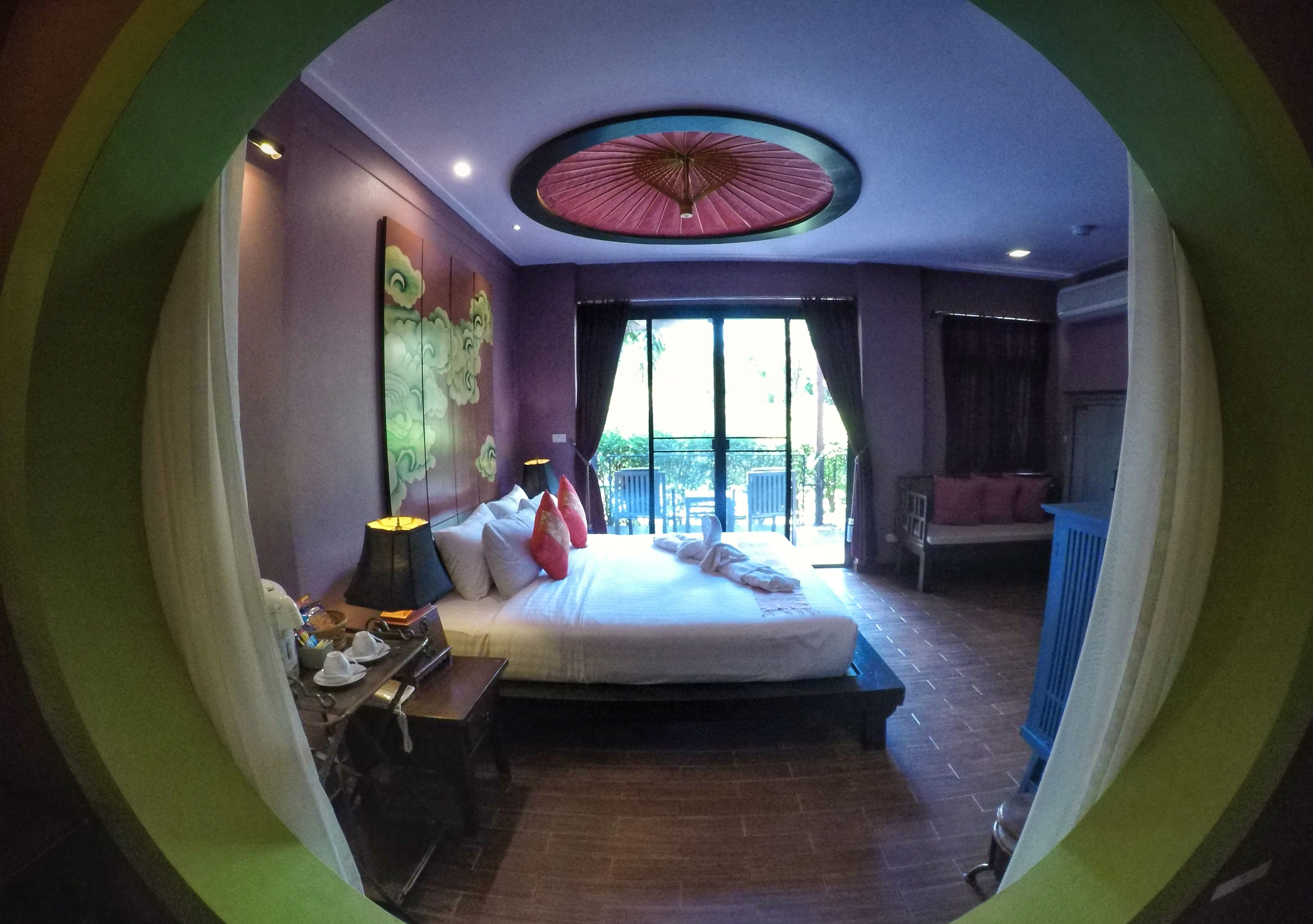 A room with a bed, a desk, a lamp, and a view of the outdoors.