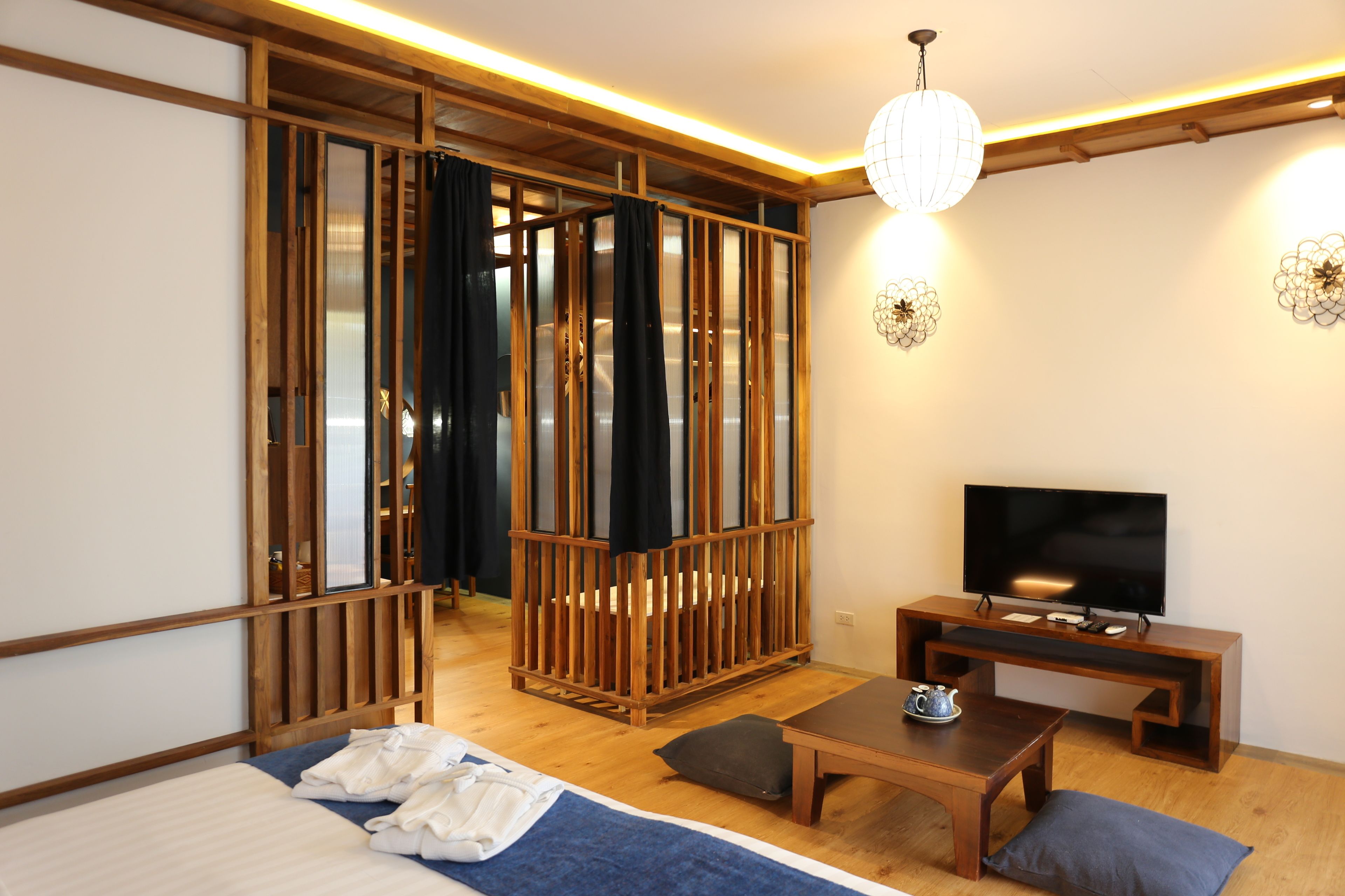 A modern room with a bed, a wooden TV stand, a table, and a sliding door.