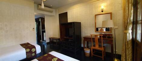 A hotel room with two beds, a desk, a television, and a mirror.