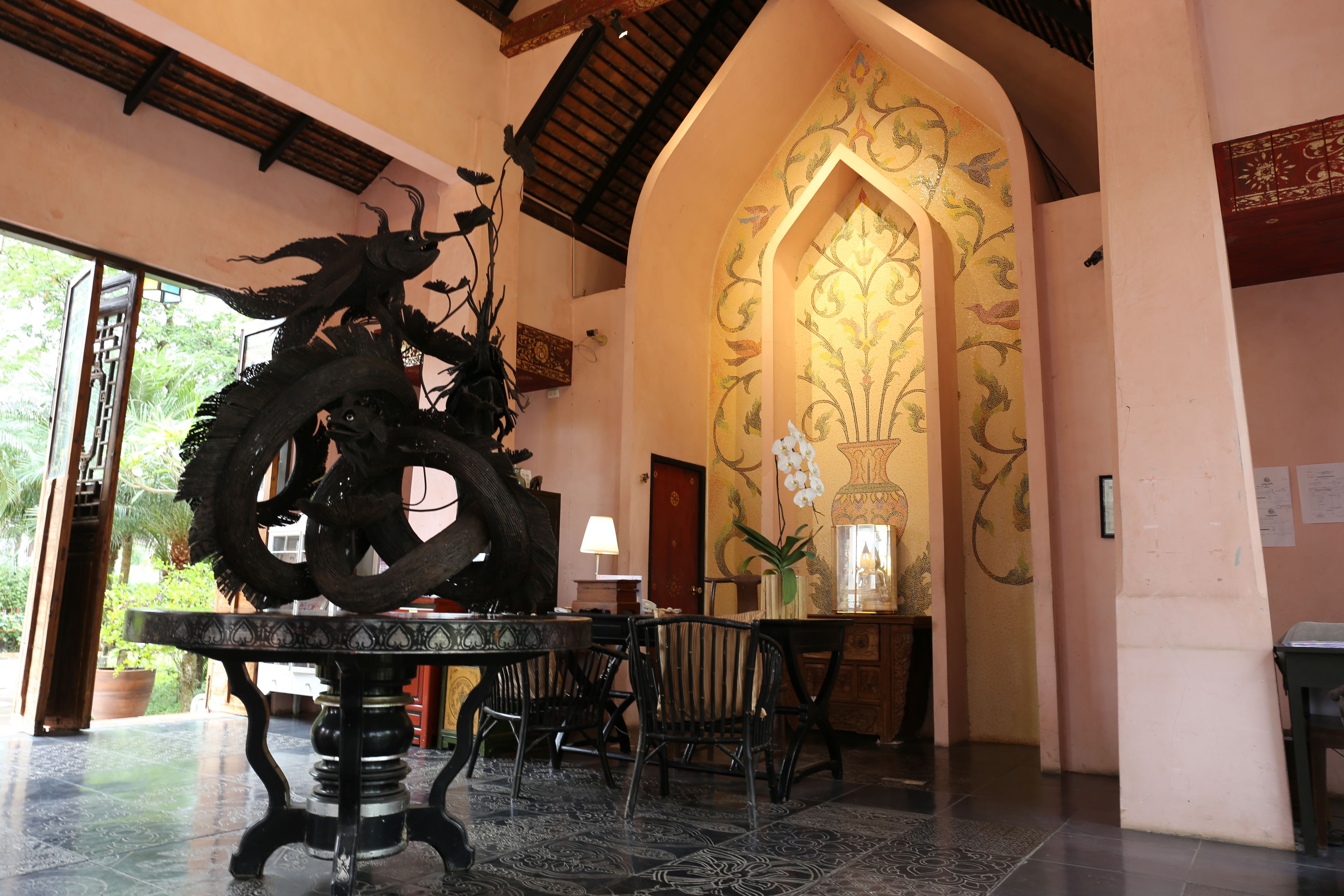 Zona de recepción con una gran escultura decorativa, una silla tradicional y una mesa.