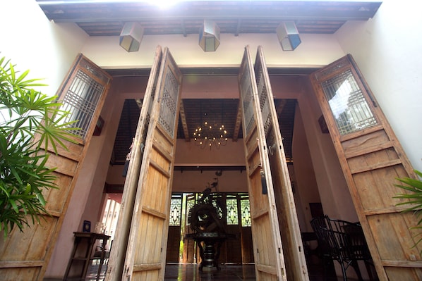A traditional wooden entrance with a central fountain, flanked by wooden doors with glass panels. - Tharaburi Resort Sukhothai (Sukhothai)