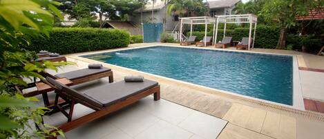 A swimming pool with lounge chairs and a pergola.