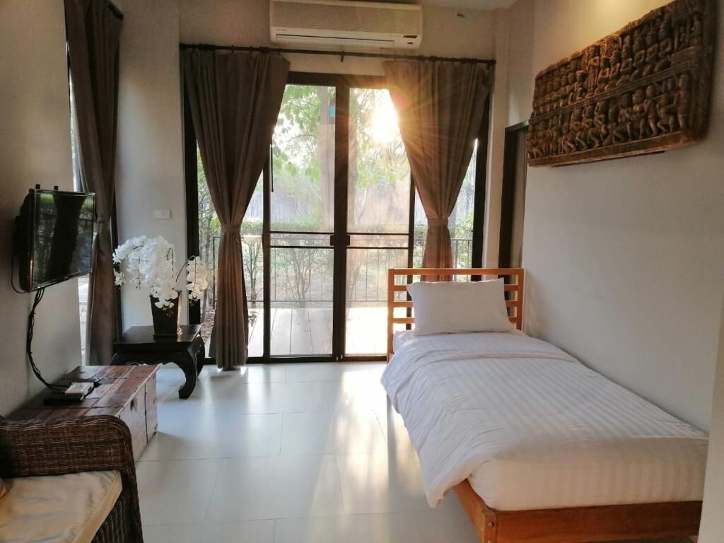 Un dormitorio con cama, escritorio, silla y ventana con cortinas.