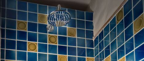Une salle de bain avec des murs recouverts de carreaux bleus et dorés et un pommeau de douche.