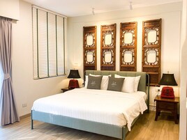 Un dormitorio ordenado con cama, mesitas de noche y espejos decorativos en la pared.