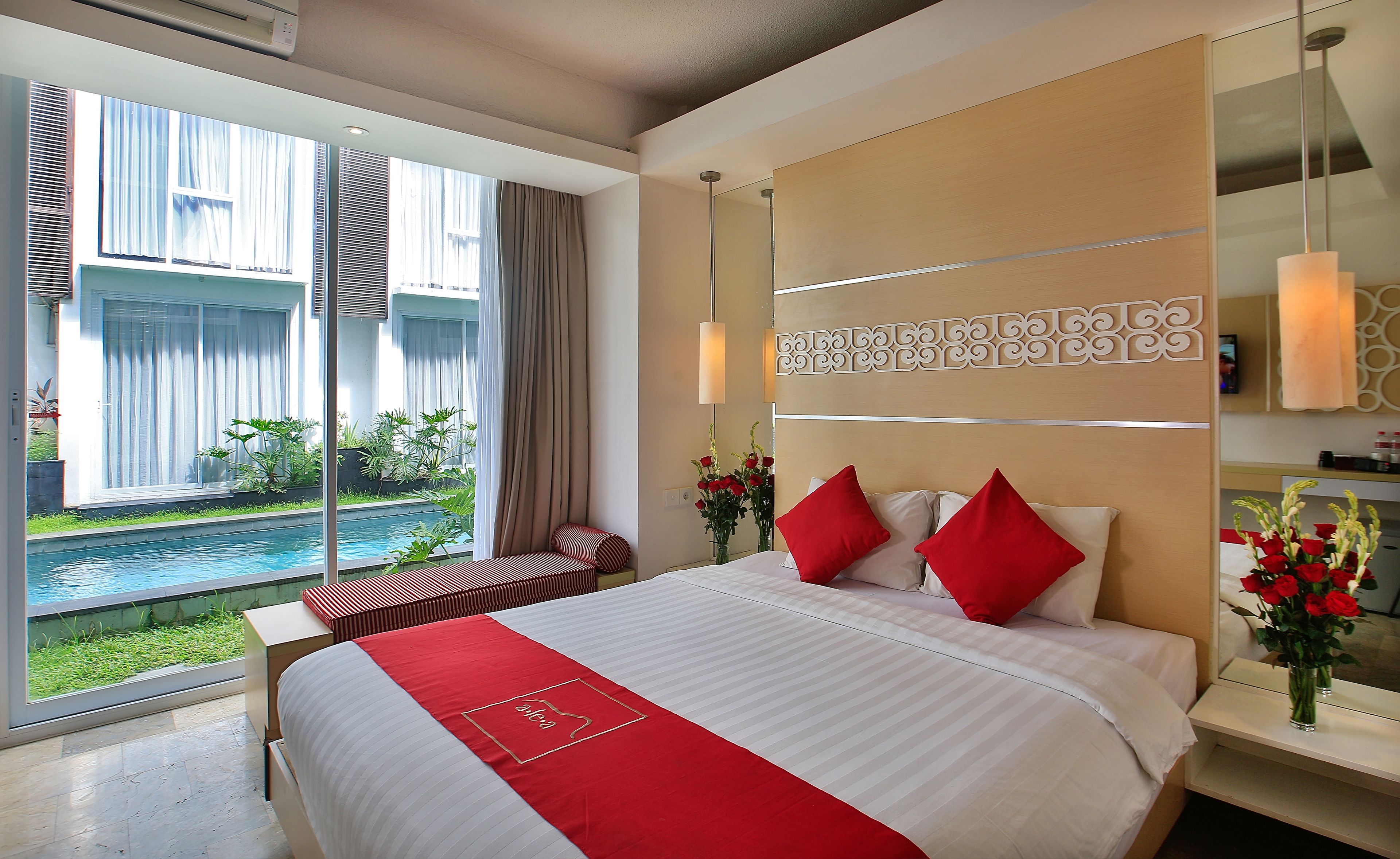 A hotel room with a large bed, a view of a pool, and a modern design.