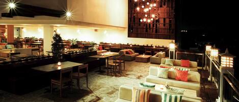A cozy outdoor seating area with stone flooring, cushioned sofas, and tables.