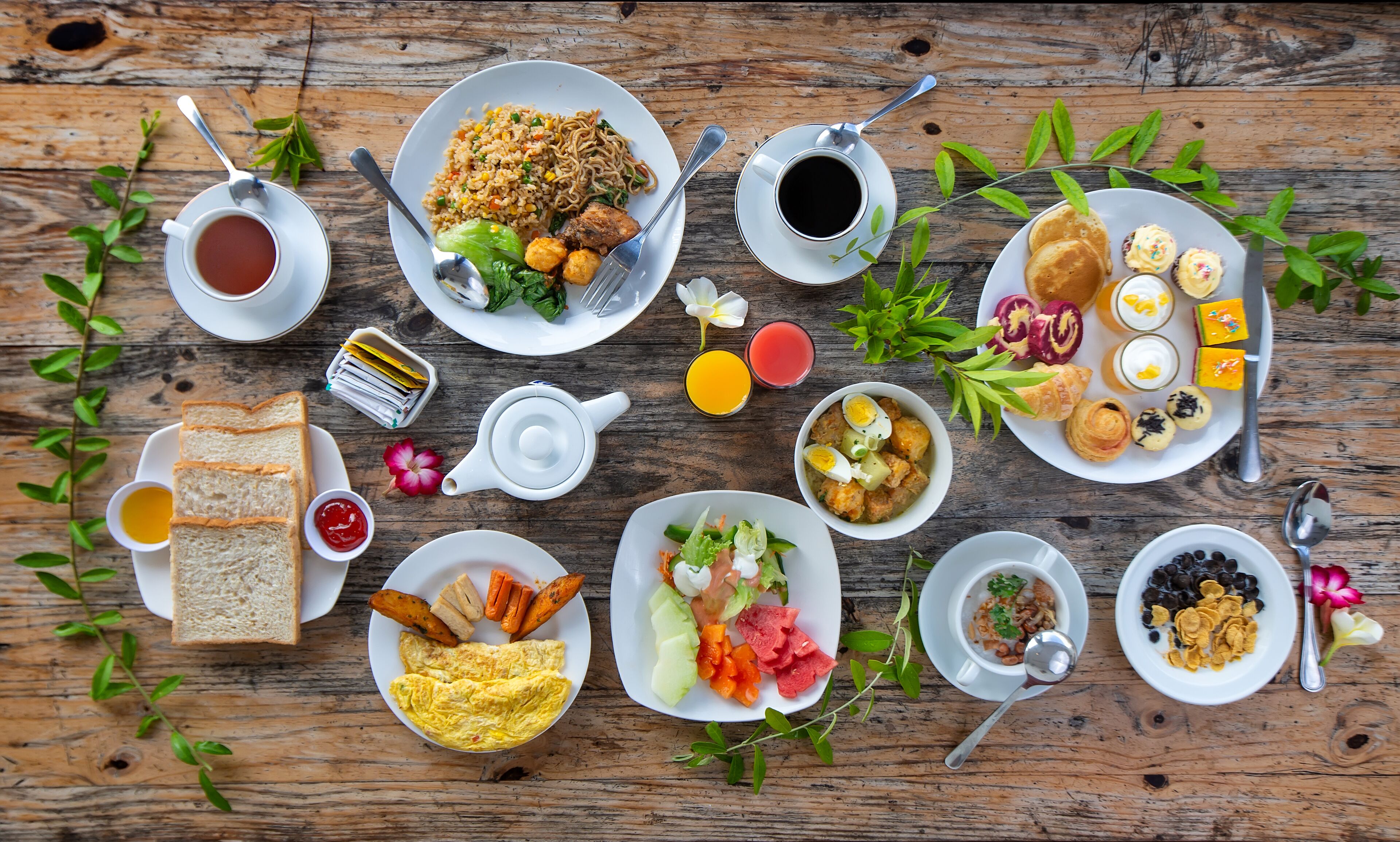 A wooden table with various breakfast dishes including eggs, toast, and fruit.